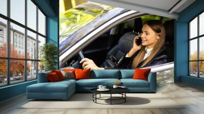 Young woman using her phone while driving the car Wall mural